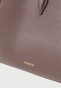 Brown textured leather handbag with gold "FURLA" logo on the front. Features a structured shape and visible stitching detailing.