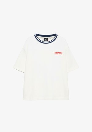 T-shirt blanc manches courtes avec col rayé bleu marine et texte rouge "COMMUNITY AT YOUR SERVICE" sur le côté gauche de la poitrine.