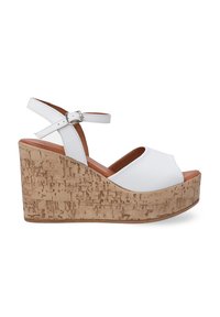 Sandales blanches à talon compensé avec une tige lisse, une sangle à la cheville avec une boucle, et une plateforme en liège texturée de couleur marron clair.