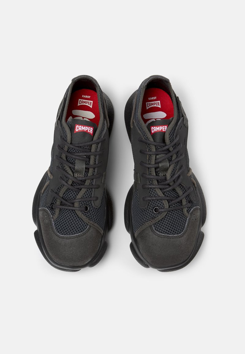 Schwarze Sportschuhe mit einem Obermaterial aus Mesh, Gummisohle und gepolsterten Akzenten. Enthält Schnürsenkel und das rote 'Camper'-Logo auf den Innensohlen.