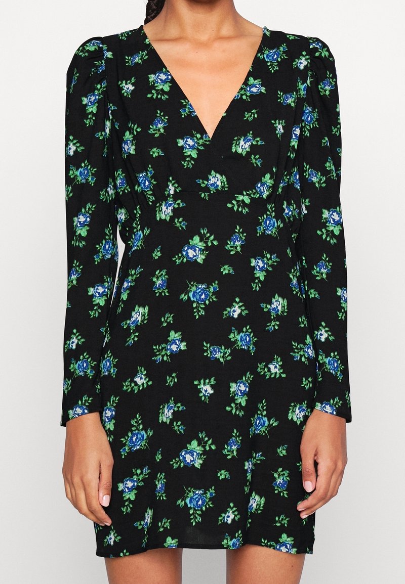 Robe fleurie noire à manches longues, avec un décolleté en V profond. Le design comprend des roses bleues et des feuilles vertes sur un tissu texturé.