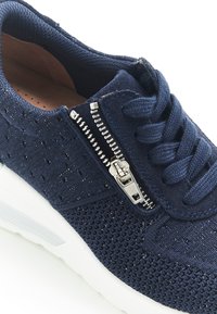 Sneaker blu navy con tessuto in rete, chiusura con zip e superficie testurizzata. Presenta una suola bianca e dettagli in pizzo.