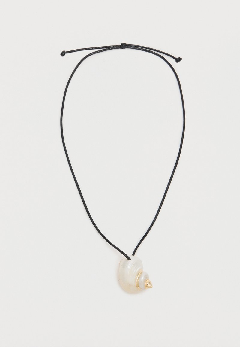 Collier cordon noir réglable avec un pendentif coquillage en spirale blanche orné d'une petite pointe dorée sur fond blanc.