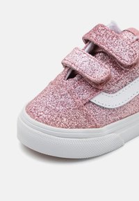 Roze glitter tenisice s bijelim detaljima, čičak trake i gumeni potplat. Gornji dio ima sjajnu teksturu i dizajn s okruglim vrhom.