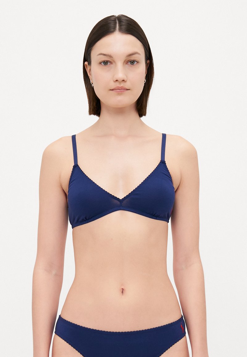 Temno modra trikotna bralette s tankimi nastavljivimi naramnicami, z valovitimi robovi in mehkim materialom. Ima preprost dizajn.