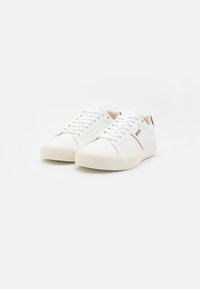 Sneaker bianche in pelle con lacci piatti, suola in gomma testurizzata e dettaglio del logo laterale. Finitura liscia con un design minimalista.