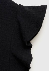 Top in maglia nera con tessuto testurizzato, maniche corte a volant e scollatura liscia. Il materiale appare morbido e leggermente elasticizzato.