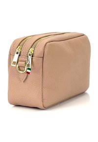 Trousse de maquillage en cuir rose doux avec une finition texturée, comportant deux fermetures éclair dorées et un petit charme représentant le drapeau italien attaché.