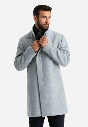 Abrigo gris claro hecho de una tela suave, con un cuello alto, cierre frontal con un botón y un corte entallado.