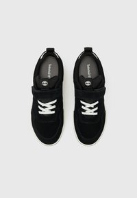 Baskets en suède noir avec des lacets blancs, un col rembourré et un accent de logo. La tige texturée présente une sangle de soutien et une semelle en caoutchouc.