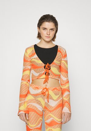 Top cropped e calças combinando em tricot texturizado nas cores laranja, amarelo e branco. O top apresenta um decote em V profundo e um fechamento frontal com laço.