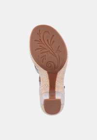 Beigen naisten kengän pohja, jossa on kuvioitu kumipohja, joka esittää kukkakuviota ja jossa on brändinimi "Gabor" kantapäällä.