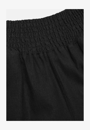 Black fabric with a gathered elastic waistband and visible vertical seam stitching for adjustable fit and comfort.