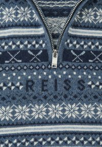 Sweter dzianinowy w odcieniach niebieskiego z zamkiem przy kołnierzu. Posiada geometryczne wzory w bieli i granacie, z wyraźnym logo "REISS" na środku.