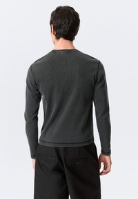 Σκούρο γκρι πουκάμισο μακρυμάνικο με ραβδωτή υφή και λαιμόκοψη. Διακοσμημένο με ραφές κατά μήκος των άκρων. Φοριέται με μαύρο παντελόνι.