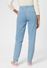 Hellblaue Jeans mit hohem Bund und geradem Bein, mit Gesäßtaschen und einfachem Bund. Gestylt mit pinken Sneakers.