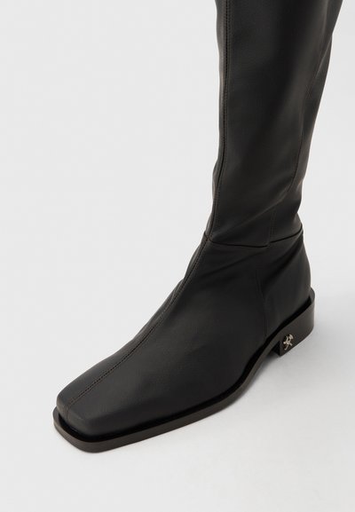 Schwarze, knöchelhohe Lederstiefel mit quadratischer Spitze, schlankem Design und niedrigem Blockabsatz mit metallischem Akzent. Glatte Textur und Nähte.