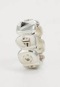 Silver ring featuring a sculptural design with rounded shapes, a triangular black gemstone, and engraved accents. Smooth texture and polished finish.