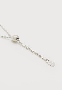 Ασημένιο κολιέ αλυσίδα με έναν μικρό γυαλισμένο στρογγυλό σύρεται και ένα επίπεδο χαραγμένο οβάλ μενταγιόν στο τέλος της αλυσίδας.