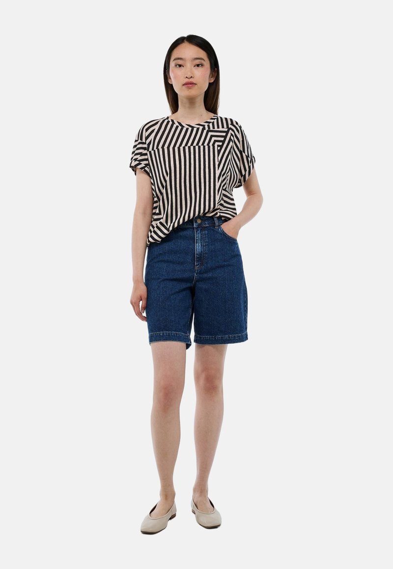 Haut à manches courtes rayé noir et crème, associé à un short en denim bleu. La tenue présente une coupe décontractée et un ourlet retroussé sur le short.