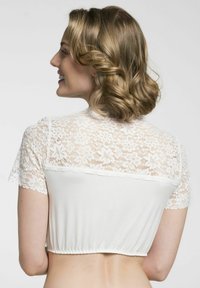 Weißes cropped Top mit durchsichtigen Spitzenärmeln und -rücken, einem gerafften Saum und floralem Spitzenmuster. Der glatte Stoff ergänzt das Spitzen-Detail.