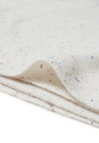 Wollen deken in gebroken wit met spikkels in bruin en blauw. Zachte textuur, netjes gevouwen met een zichtbare vouw.