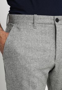 Grijze broek met visgraatmotief, gemaakt van gestructureerde stof, met een rechte snit, twee zijzakken en een knoopsluiting in de tailleband.