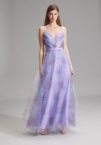 Lavendelfarbenes Abendkleid mit tiefem V-Ausschnitt, transparenter Blumenüberlage und taillierter Passform. Trägerdesign mit einem fließenden Rock. Elegante Sandalen.