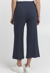 Navy ribbed knit pants with a wide leg design, featuring a high waist and soft texture, paired with white sneakers.
