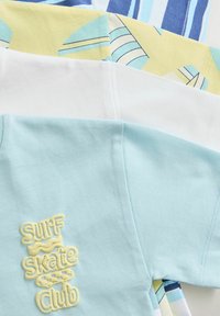 Keturi marškiniai trumpomis rankovėmis, sukrauti vienas ant kito: šviesiai mėlynas su geltonu tekstu "Surf Skate Club", baltas ir raštuoti geltoni bei mėlyni stiliai. Skirtingos medvilnės medžiagos.