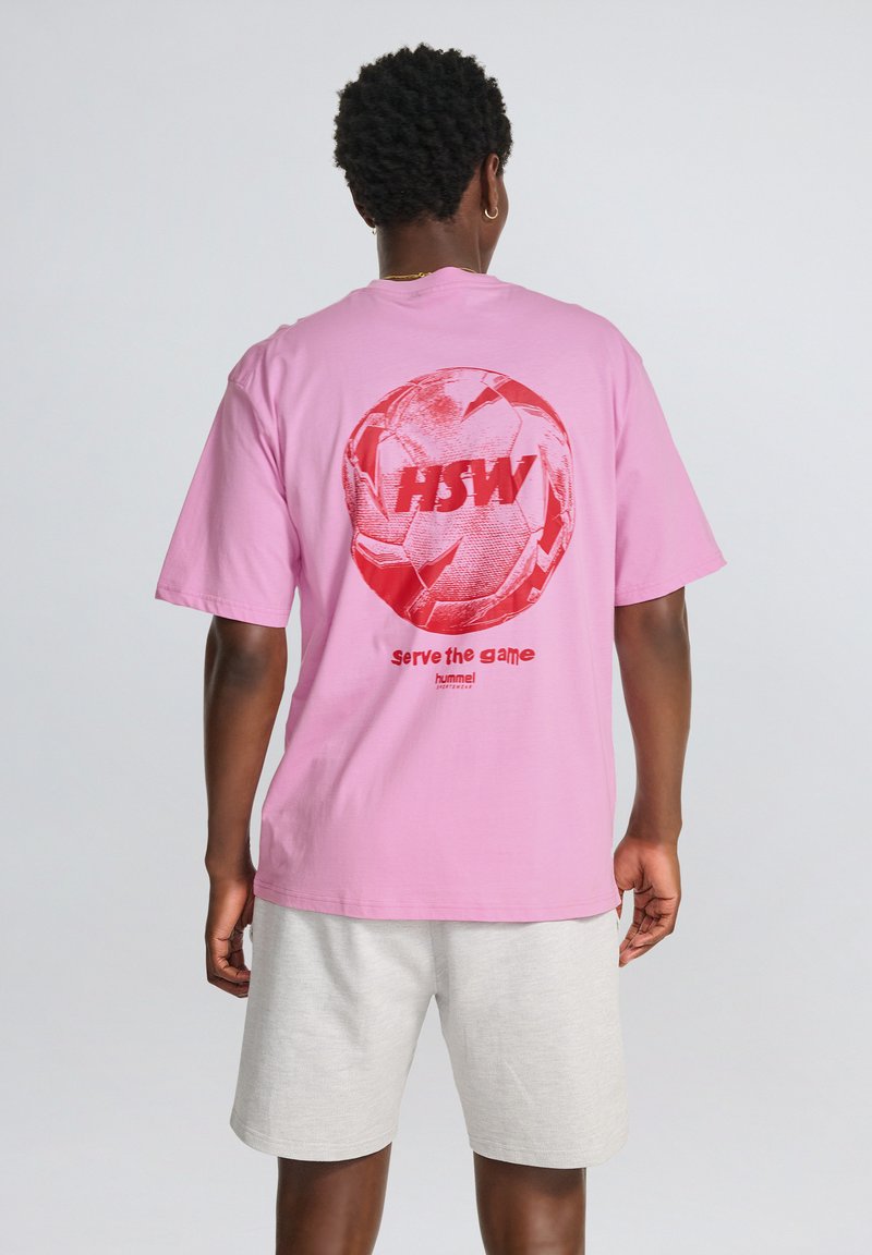 Pink bomulds t-shirt med et stort rødt grafisk motiv af en fodbold og teksten "HSW" samt "serve the game" på ryggen. Korte ærmer.