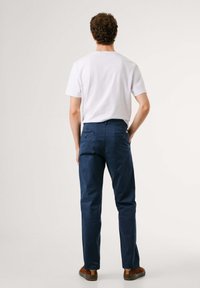 Chinos azul marino con un corte recto, que presentan dos bolsillos traseros y una textura suave, combinados con una camiseta blanca de manga corta.