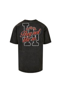 Sort bomulds t-shirt med korte ærmer og rund halsudskæring. Trykt tekst på ryggen i rød og hvid læser "De kan ikke lide os."