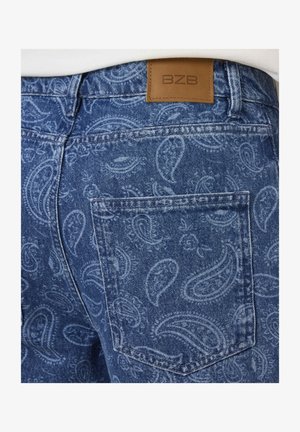 Jean en denim avec motif paisley bleu clair, poche arrière visible et patch en cuir marron marqué BZB à la ceinture.