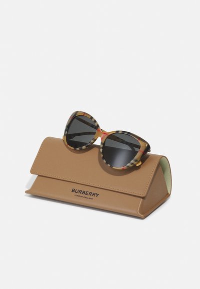 Lunettes de soleil Burberry avec une monture à motifs dans des nuances de jaune, noir et rouge, reposant sur un étui rectangulaire brun avec un logo gravé.