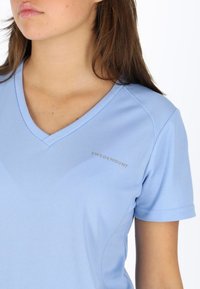 Lyseblå kortærmet t-shirt i åndbart materiale med en v-halsdesign og et lille "SWEDEMOUNT" logo på venstre bryst.