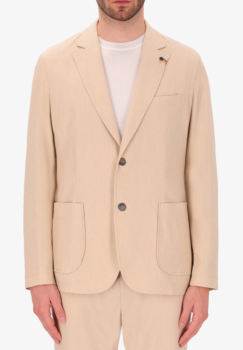 Blazer beige con chiusura a due bottoni, revers a scalpello e tasche a toppa. Realizzato in tessuto testurizzato, presenta una piccola spilla multicolore.