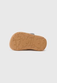 Semelle de chaussure gris clair avec caoutchouc texturé arborant un motif de feuille ; comprend le logo "bisgaard". Forme arrondie avec un design flexible.