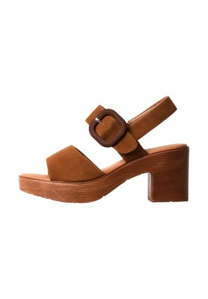 Sandalia marrón de ante con puntera abierta, tacón de bloque de madera grueso, tira frontal ancha y correa ajustable en el tobillo con hebilla grande cuadrada.