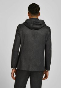Grijze hoodiejas van textuurstof, met een getailleerde silhouette en twee knopen op de manchetten. De achterkant heeft een strakke, minimalistische uitstraling.