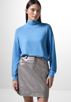 Blauwe langemouwen turtleneck trui gecombineerd met een metallic zilveren minirok. De trui is zacht en de rok heeft een gladde, glanzende textuur.