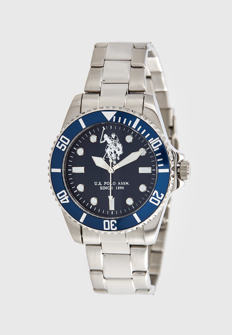 Zilveren roestvrijstalen horloge met een blauwe lunette, zwarte wijzerplaat, witte uurmarkeringen en een logo van een polo-speler. Voorzien van een metalen armband.