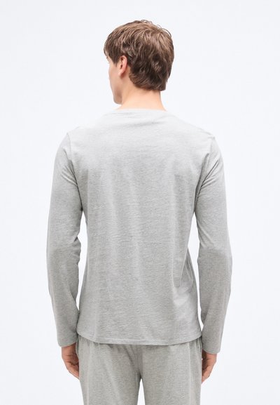 Šedé tričko s dlouhým rukávem z měkké látky, se zaobleným výstřihem a plochými švy. Zadní strana má hladkou texturu bez ozdob.