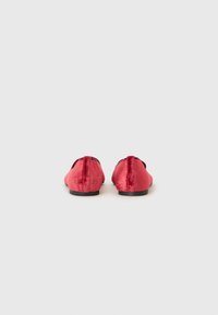 Pantofi slip-on din catifea roșie, cu o textură netedă, vârf rotund și un toc jos de culoare neagră. Vederea din spate evidențiază un design elegant și minimalist.