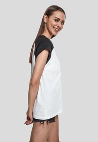 Camiseta negra y blanca de manga corta con escote redondo y corte relajado, combinada con pantalones cortos grises con detalle de cordón.