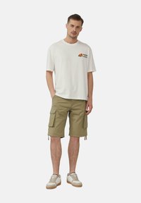 Lichte katoenen t-shirt in crème met "Papaya" graphic, gecombineerd met olijfgroene cargoshorts met zijzakken en verstelbare zoom.