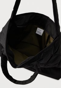 Μαύρη τσάντα tote με ανάγλυφη υφή, κλείσιμο με φερμουάρ, υφασμάτινους χειρολαβές και λείες εσωτερικές επενδύσεις σε ελαιόλαδο πράσινο. Περιέχει ετικέτα φροντίδας στο εσωτερικό.