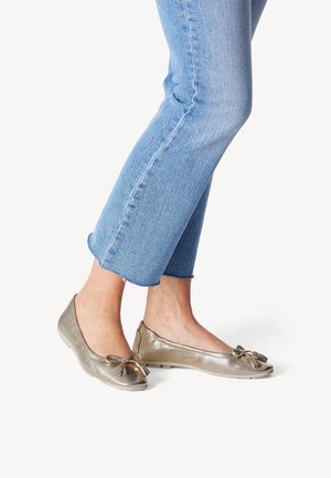Metallic graue Ballerinas mit einer Schleifendetail an der Spitze, kombiniert mit hellblauen, gekürzten Jeans mit ausgefranster Säume und subtiler Textur.