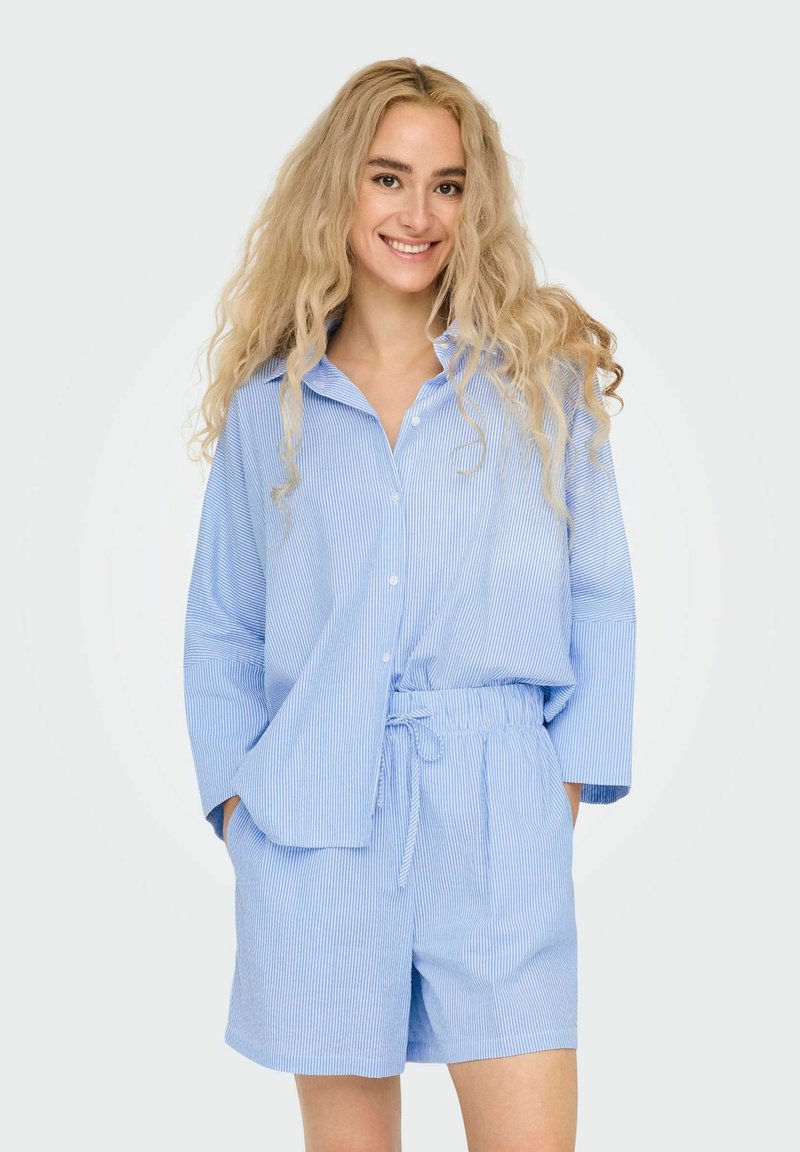 Blauw gestreepte knopshirt met losse mouwen, gecombineerd met korte broek met elastische taille, beide gemaakt van lichtgewicht stof.