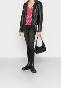 Veste de motard en cuir noire, haut floral rouge, jeans skinny noirs, bottines noires et un sac à main en cuir noir crocodile.